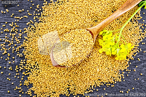 Image of Mustard seeds in spoon with flower on board top