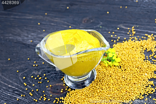 Image of Sauce mustard in sauceboat with flower on wooden board