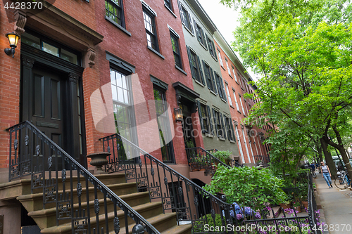 Image of Row of old brownstone buildings along an empty sidewalk block in the Greenwich Village neighborhood of Manhattan, New York City NYC