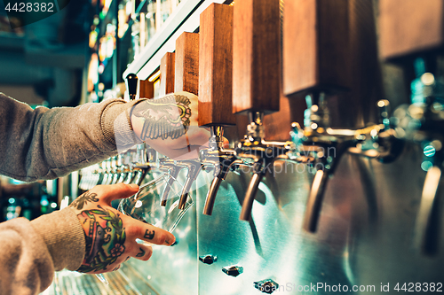 Image of Hand of bartender pouring a large lager beer in tap.