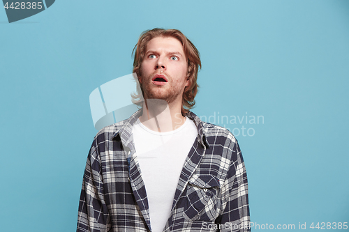 Image of The young attractive man looking suprised isolated on blue