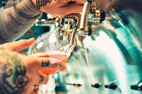 Image of Hand of bartender pouring a large lager beer in tap.