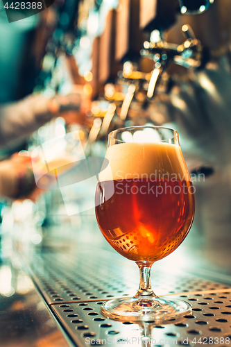 Image of Hand of bartender pouring a large lager beer in tap.