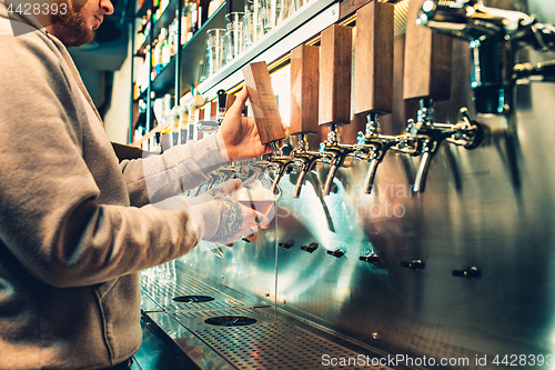 Image of Hand of bartender pouring a large lager beer in tap.