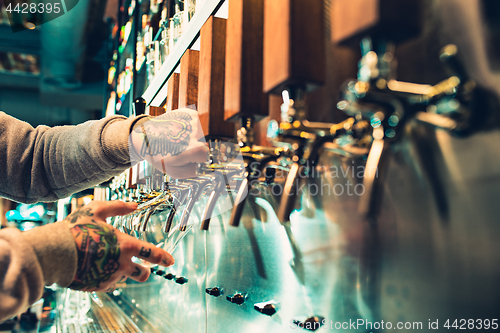 Image of Hand of bartender pouring a large lager beer in tap.