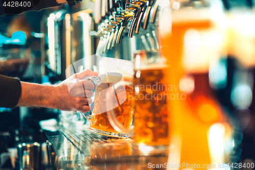 Image of Hand of bartender pouring a large lager beer in tap.