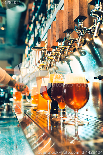 Image of Hand of bartender pouring a large lager beer in tap.
