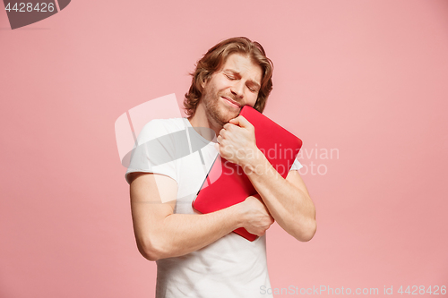 Image of Businessman hugging laptop on pink