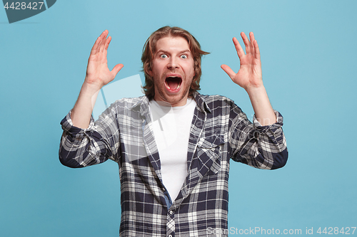 Image of The young attractive man looking suprised isolated on blue