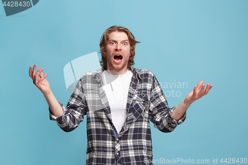 Image of The young attractive man looking suprised isolated on blue