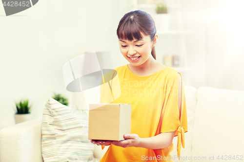 Image of happy asian young woman with parcel box at home