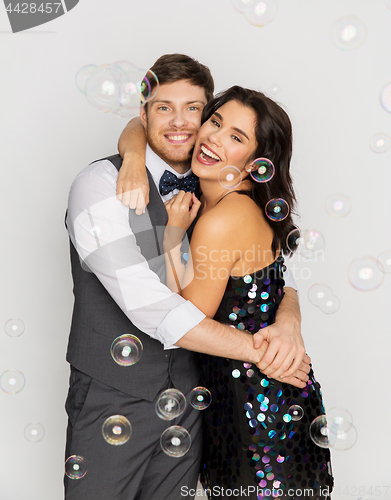 Image of happy couple hugging in soap bubbles at party