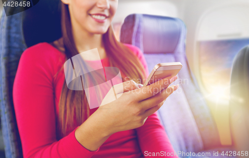 Image of close up of woman sitting in plane with smartphone