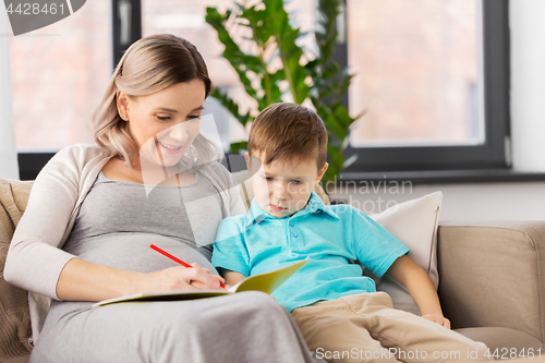Image of pregnant mother with workbook and son at home