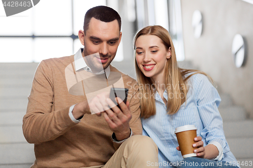 Image of man and woman with smartphone at office stairs