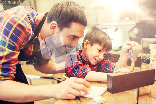 Image of dad and son with ruler measuring plank at workshop