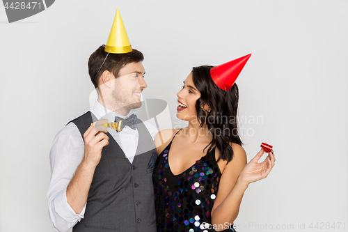 Image of happy couple with party blowers having fun