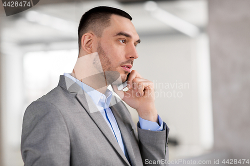 Image of businessman calling on smartphone at office