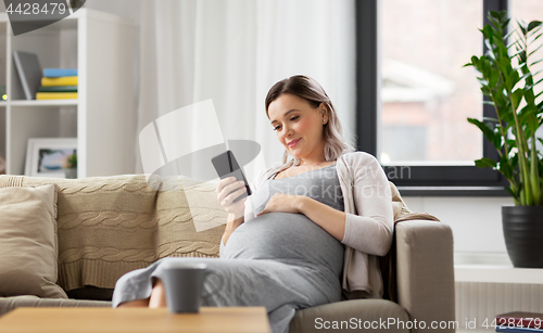 Image of happy pregnant woman with smartphone at home