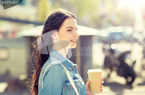 Image of happy young woman drinking coffee on city street