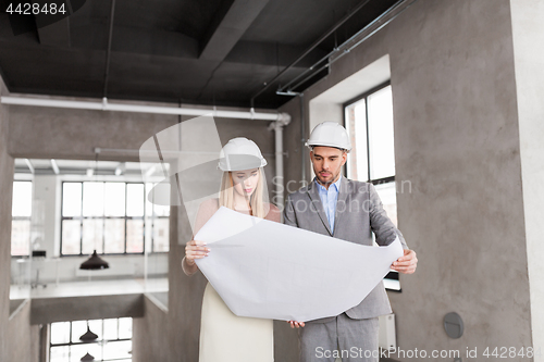 Image of architects with blueprint and helmets at office