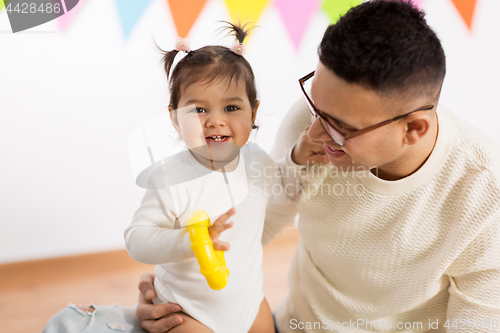 Image of happy father and little daughter at birthday party