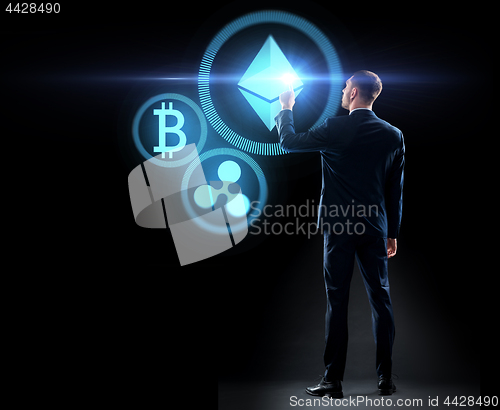 Image of buisnessman with cryptocurrency holograms