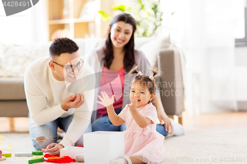 Image of baby girl with birthday gift and parents at home 