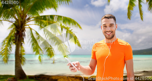 Image of man with smartphone and earphones over beach