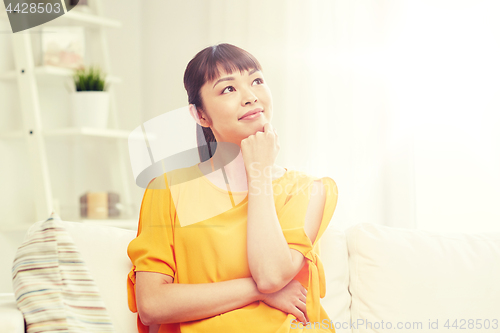 Image of happy asian young dreaming woman at home