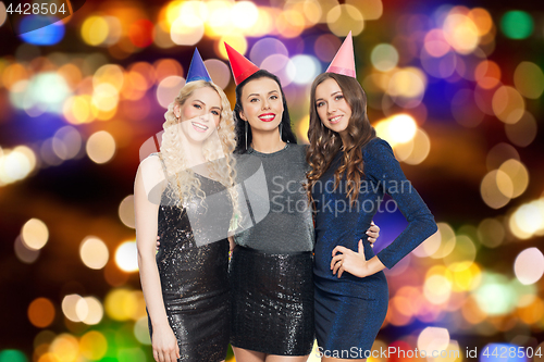 Image of happy women with party caps hugging over lights