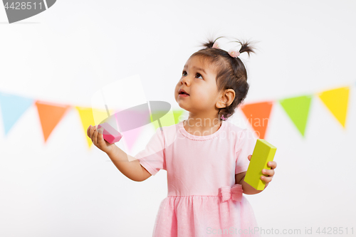 Image of happy baby girl with toy blocks at birthday party