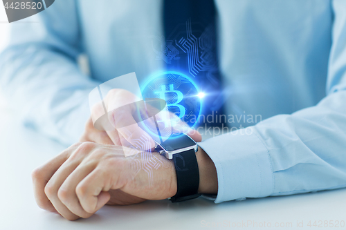 Image of close up of hands with bitcoin on smart watch