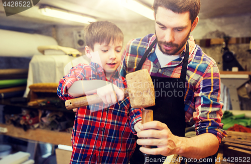 Image of father and son with chisel working at workshop