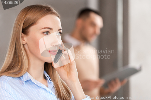 Image of businesswoman calling on smartphone at office