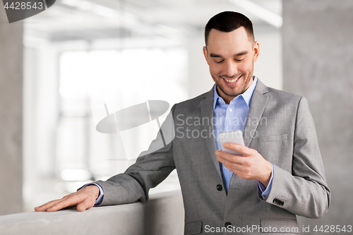 Image of smiling businessman with smarphone at office
