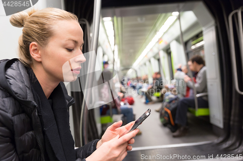 Image of Young girl reading from mobile phone screen in metro.