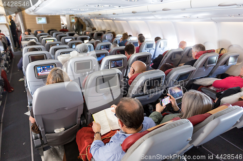 Image of Interior of large commercial airplane with passengers on their seats during flight.