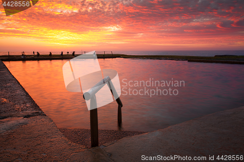 Image of Ocean rock pool under blazing red sky