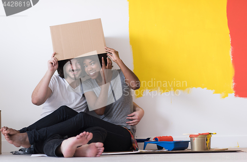 Image of young multiethnic couple playing with cardboard boxes