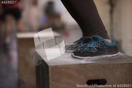 Image of black woman is performing box jumps at gym