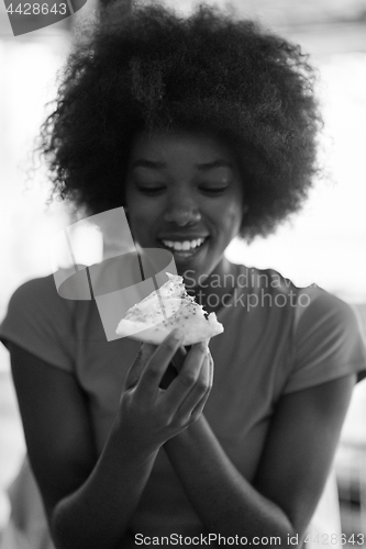 Image of woman with afro hairstyle eating tasty pizza slice