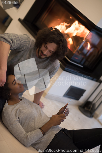 Image of multiethnic couple using tablet computer on the floor