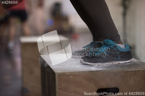 Image of black woman is performing box jumps at gym