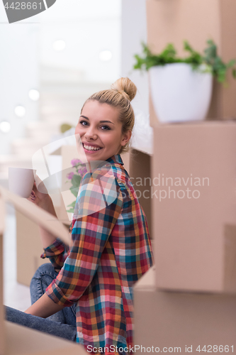 Image of woman with many cardboard boxes sitting on floor