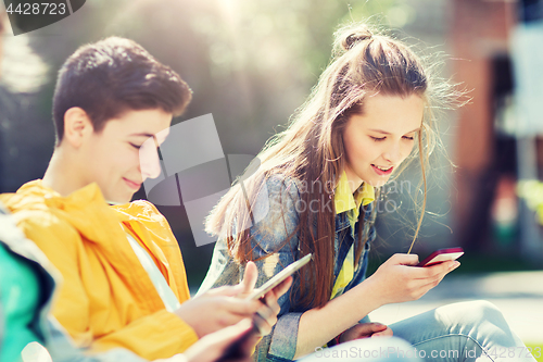 Image of happy teenage friends with gadgets outdoors