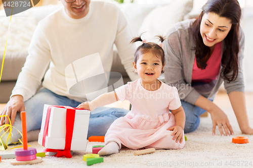 Image of baby girl with birthday gift and parents at home 