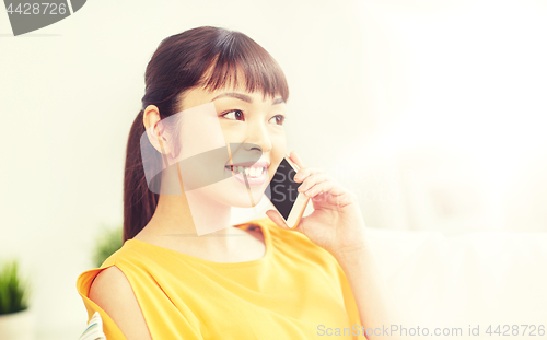 Image of happy asian woman calling on smartphone at home