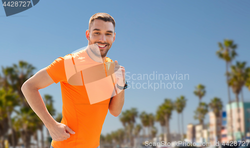 Image of smiling young man running at summer seaside