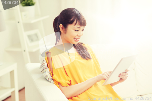 Image of happy young asian woman with tablet pc at home